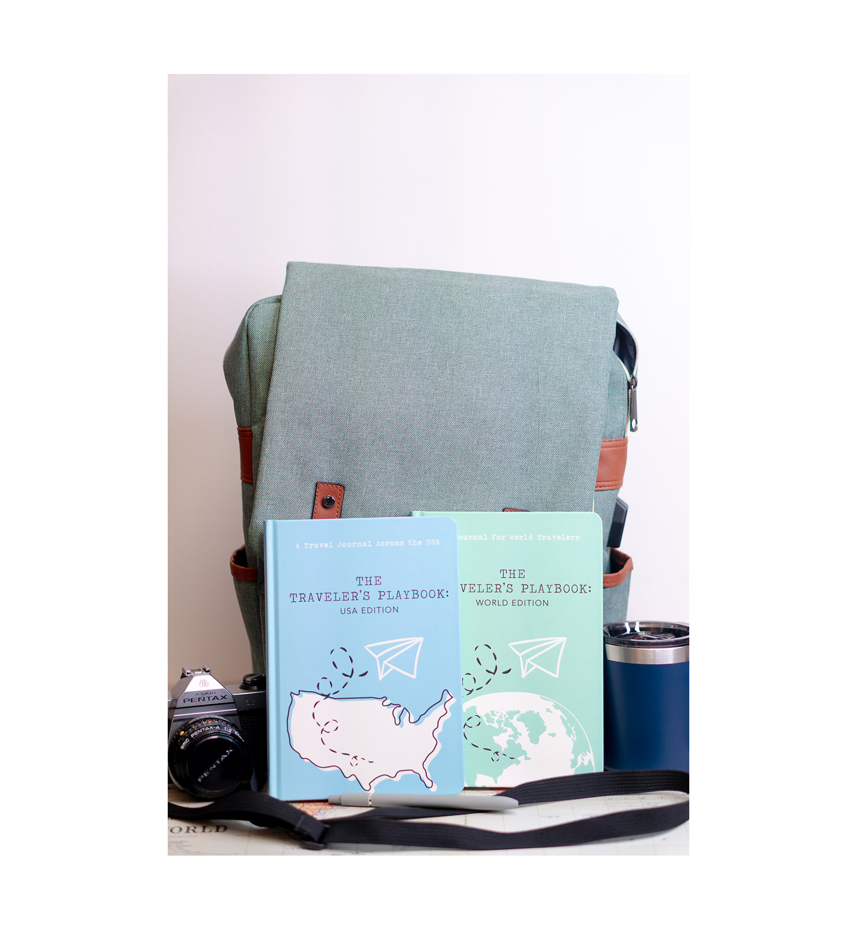 World and USA travel journals in front of a travel backpack
