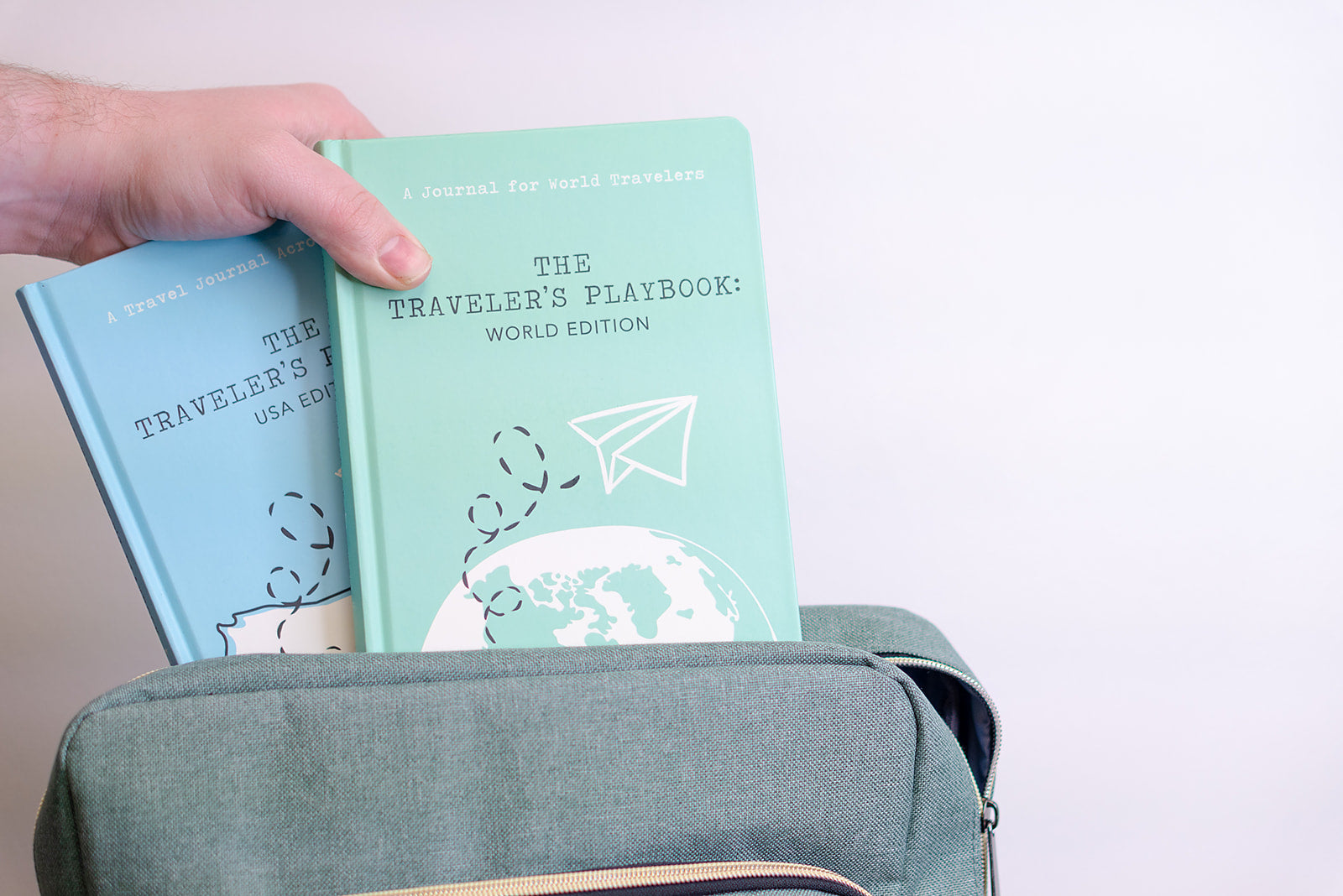 USA and world travel journal being placed inside a travel backpack, ready for adventures ahead