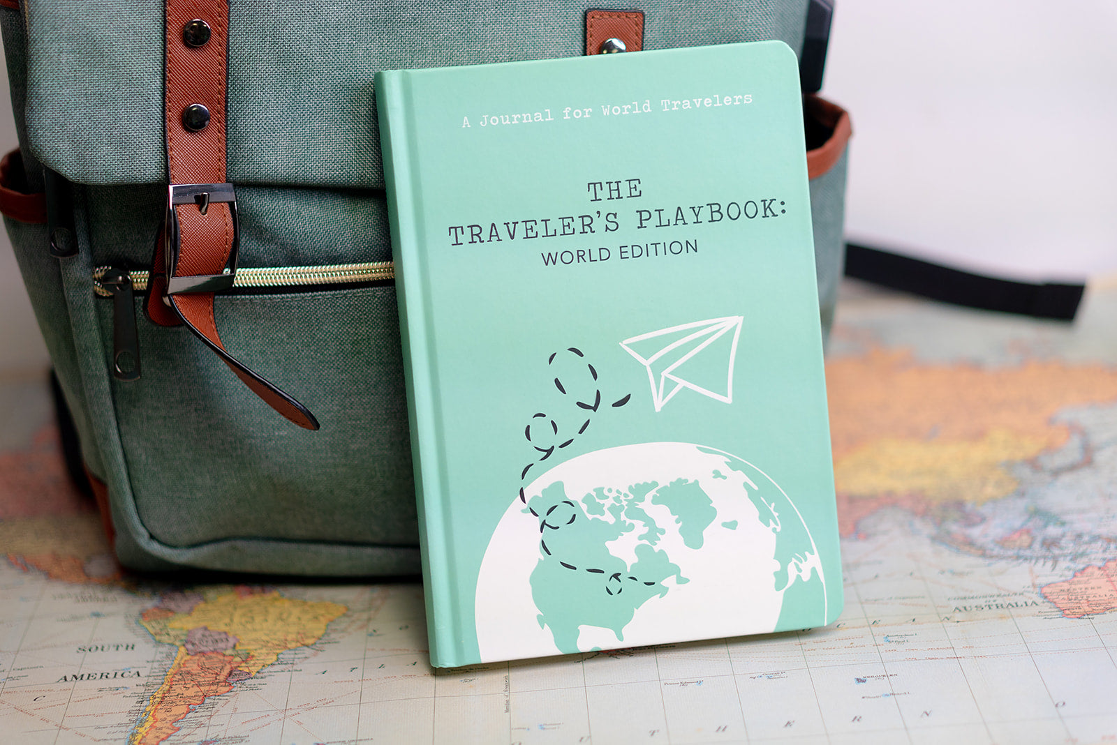 World travel journal placed in front of a backpack, ready for adventures ahead